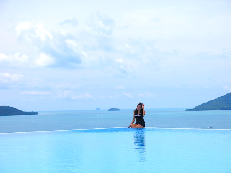 Raevian sitting on pool edge with gorgeous sea view